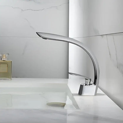 Modern chrome-finished basin faucet with sleek curved spout and square base complementing decorbites brushed gold basin design