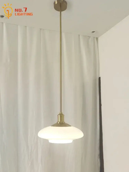 A sleek brass pendant light with frosted glass shade featured among modern brushed nickel glass pendant lights for home decor
