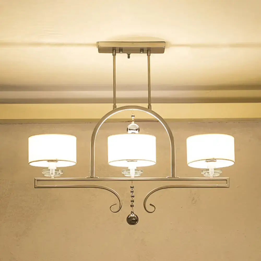 Modern brushed nickel island pendant light with three white fabric shades and crystal accents for dining room use