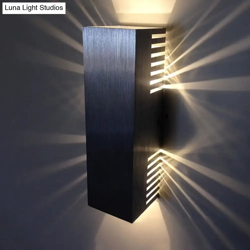 Modern brushed silver wall light with vertical slats emitting warm white light for bedroom sconce lighting