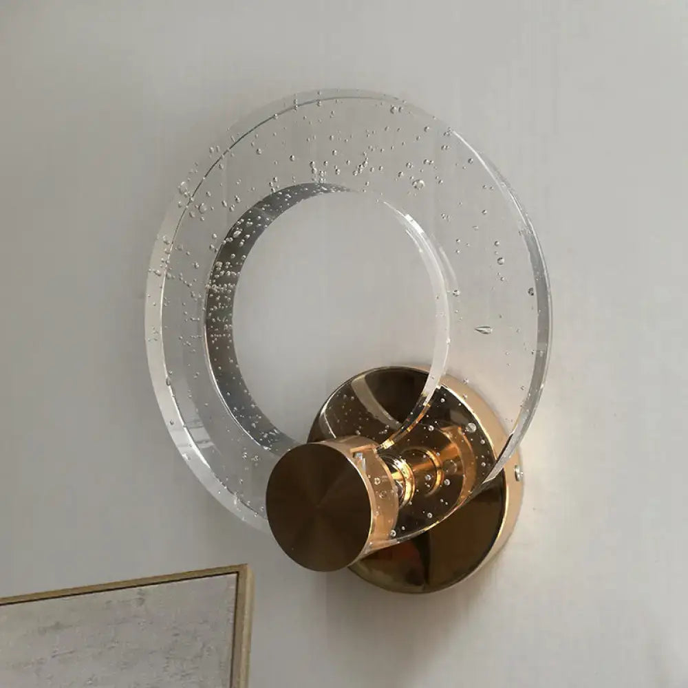Modern wall lamp with clear bubble-infused glass ring and polished brass base designed for 220v-240v bedroom lighting