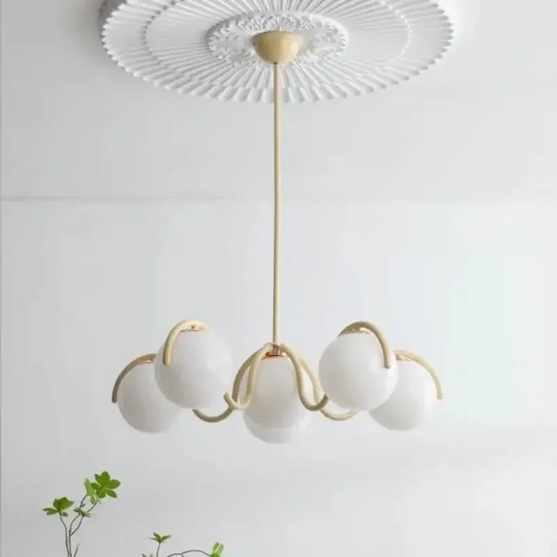 A modern design pendant light with five frosted rounded glass globes and gold-toned arms for dining room use