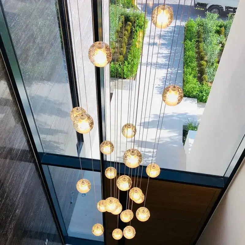 A modern cascading crystal ball led pendant light with warm golden glass orbs for living room decorbites pendant light