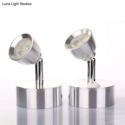 Two chrome adjustable spotlight wall sconces with metal shades and a small red power button emitting warm white light