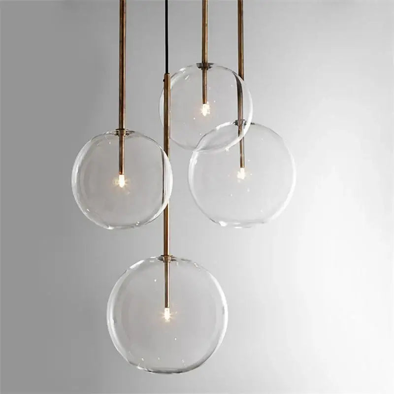Modern chrome and brass pendant light with clear glass globe and visible filament bulbs for kitchen lighting