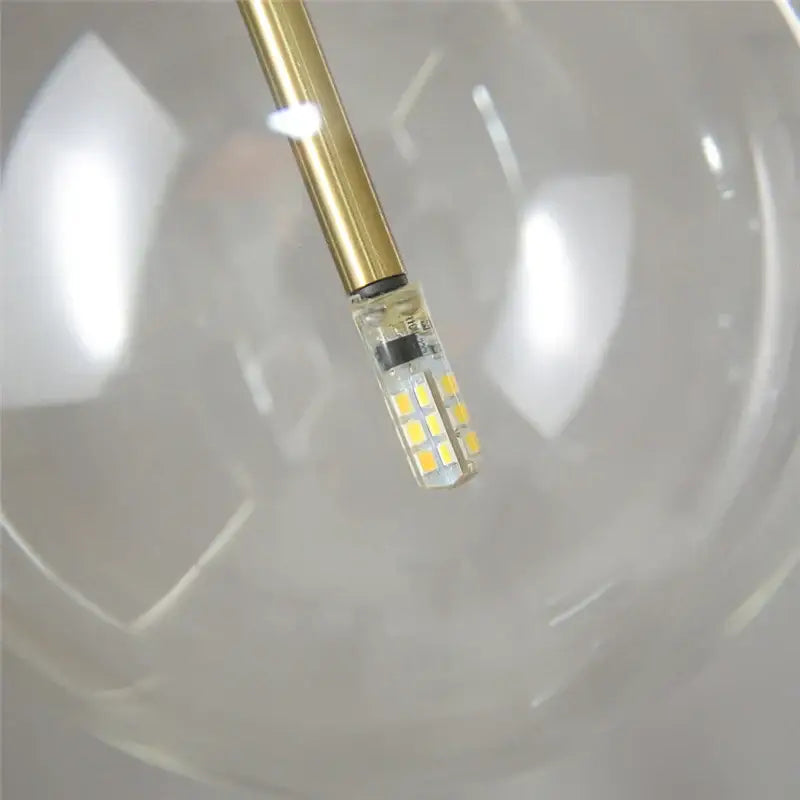 Modern chrome and brass pendant light with a clear glass globe and gold-finished led bulb for kitchen lighting