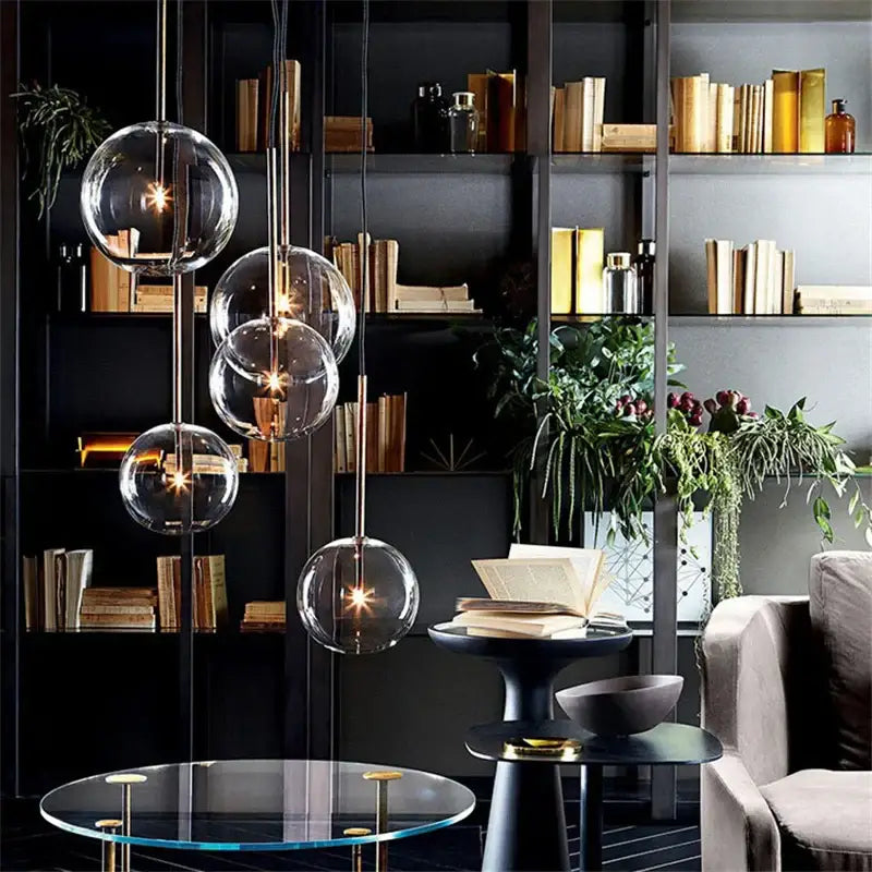 Modern chrome and brass pendant light with clear glass globe and warm bulbs suspended from slender rods for kitchen use