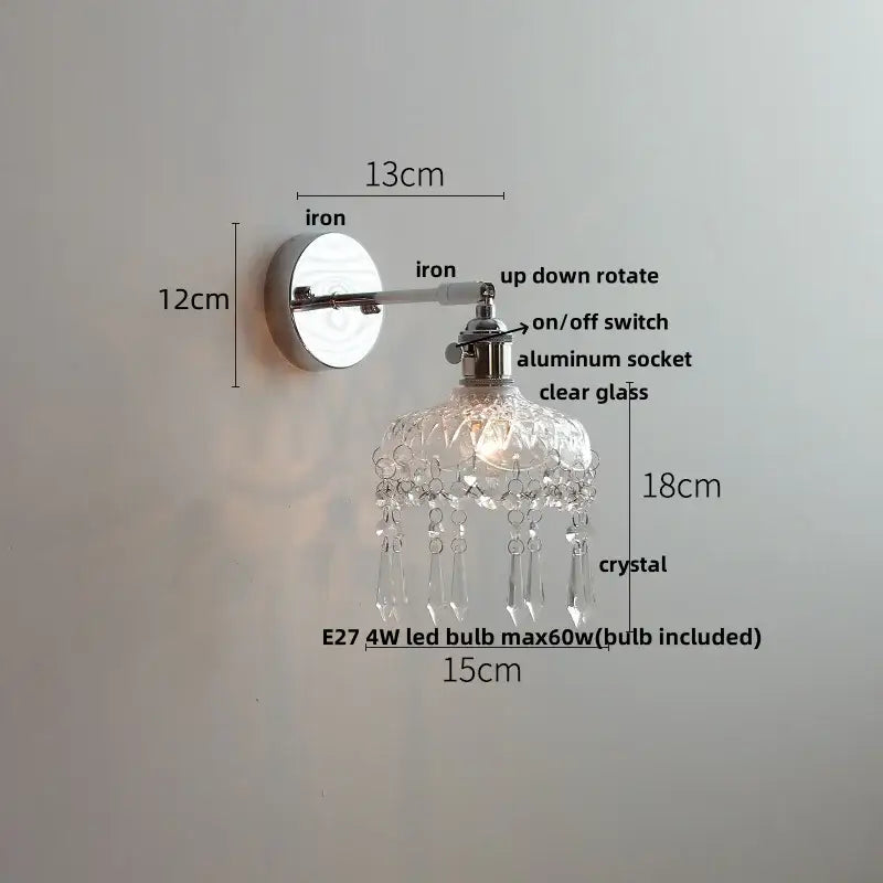 Modern chrome wall light fixture with polished iron base, adjustable arm, clear glass shade, and crystal droplets for bedroom use