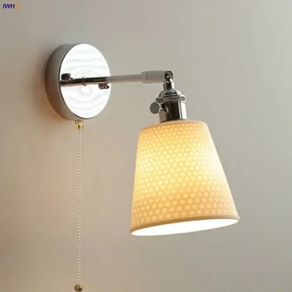 Modern chrome and perforated fabric wall light fixture with warm-toned lampshade and polished chrome arm for bedroom use