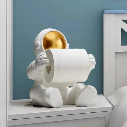 White astronaut tissue box figurine with gold visor holding roll of toilet paper modern chrome design for living room