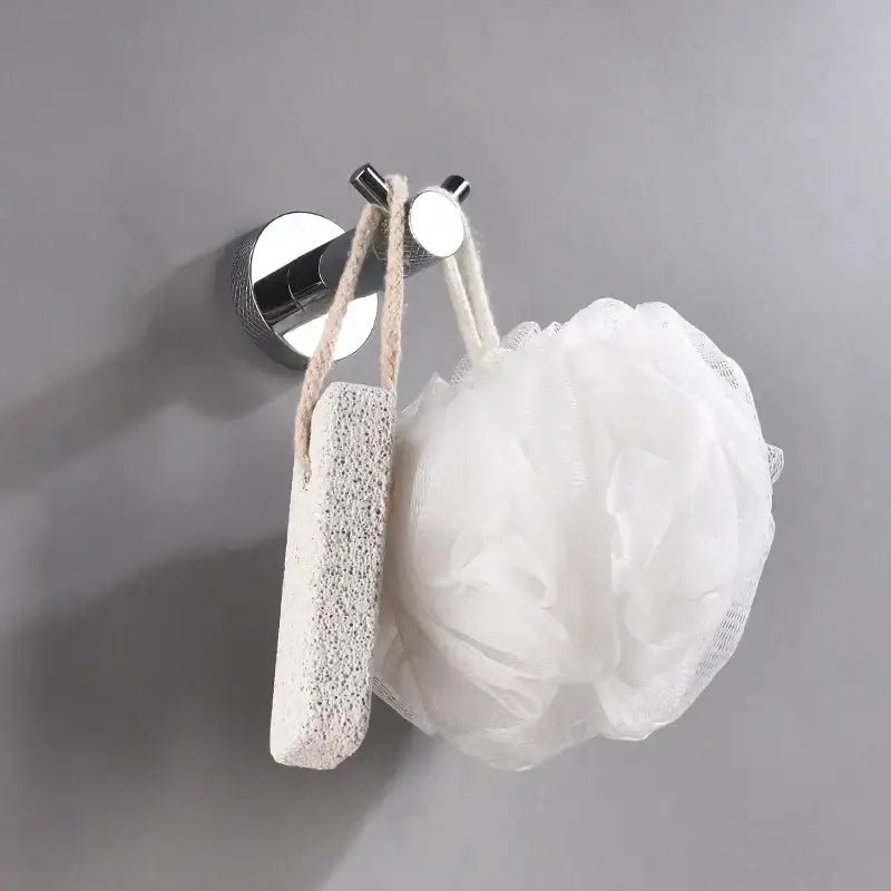 White loofah hanging from a chrome hook in modern chrome bathroom essentials set by decorbites bathroom essentials