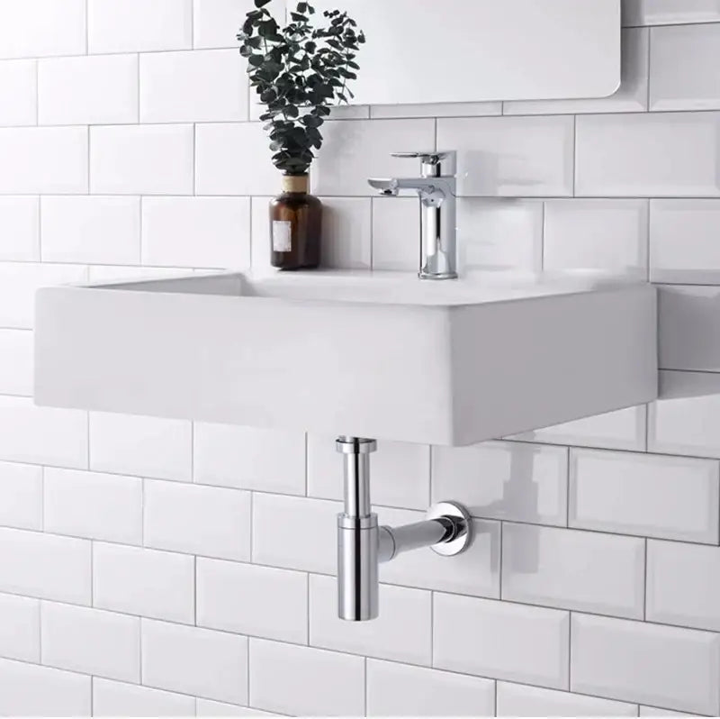Modern white wall-mounted sink with a sleek chrome decorbites brass round bottle trap and matching drain pipe