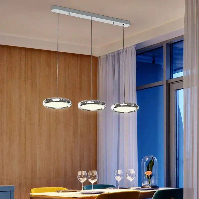Modern chrome circular dining pendant led light with sleek glass shades on a minimalist rectangular ceiling fixture