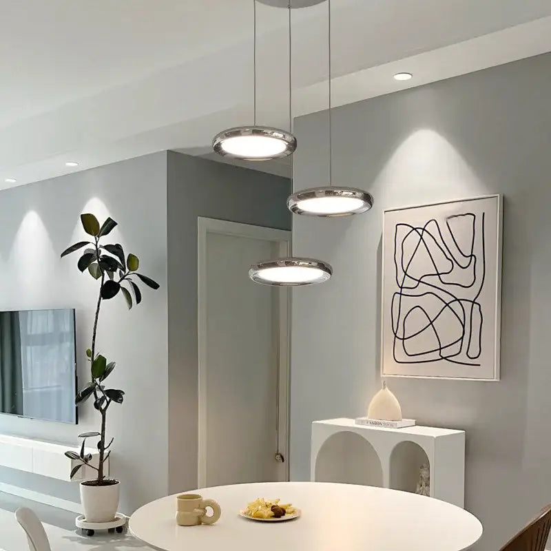 Three modern chrome circular dining pendant led lights with sleek frames and soft white illumination for kitchen decorbites