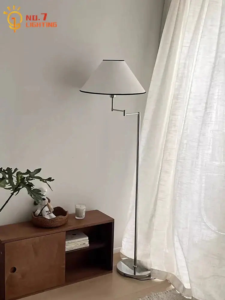 A sleek silver chrome floor lamp with cream rocker arm and white conical shade with black trim for living room