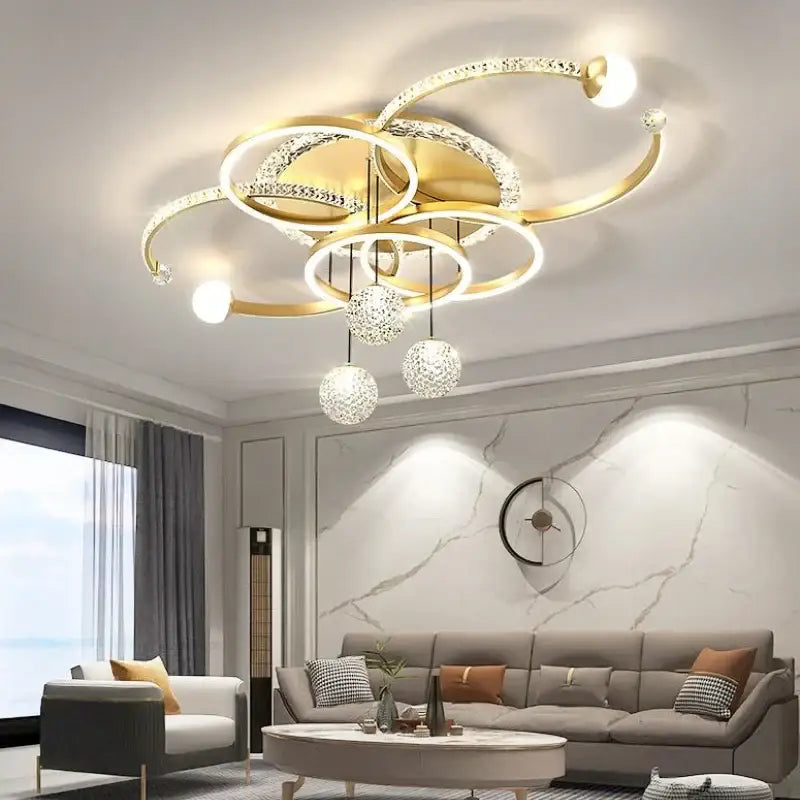 Gold-toned modern chrome crystal led pendant chandelier with interlocking rings and dangling crystal spheres for dining room