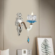Elegant modern chrome finish wall light with clear glass candle holder and blue crystal accents for bedroom use