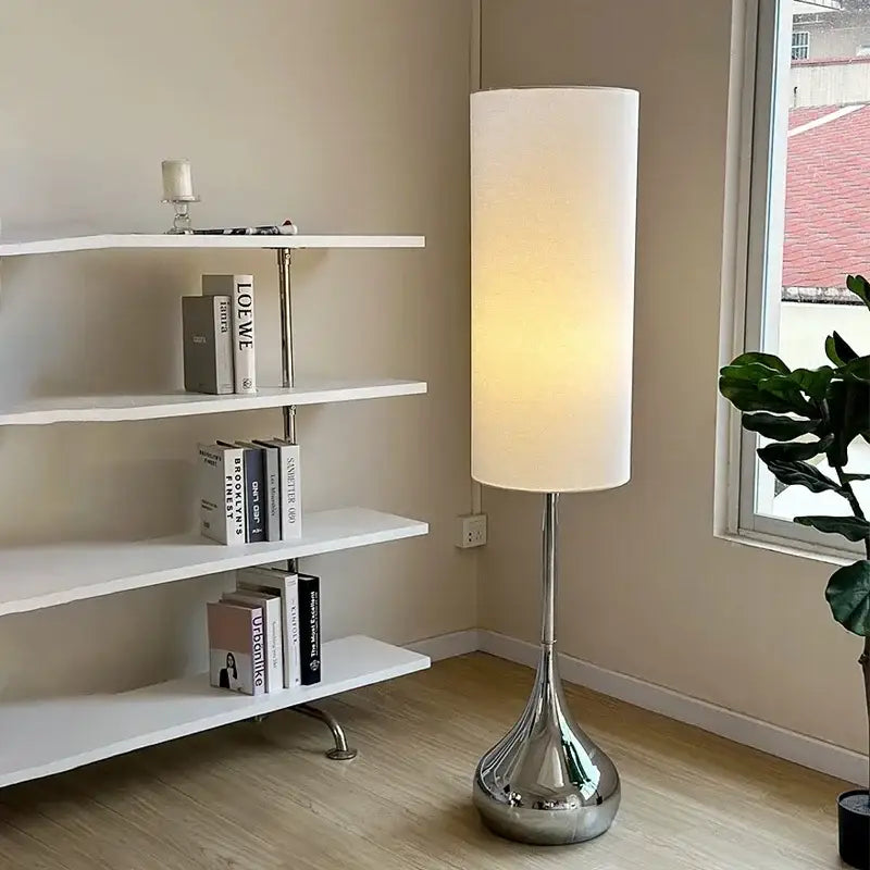 Modern chrome floor lamp with cream fabric shade featuring a tall cylindrical design for stylish living room decorbites
