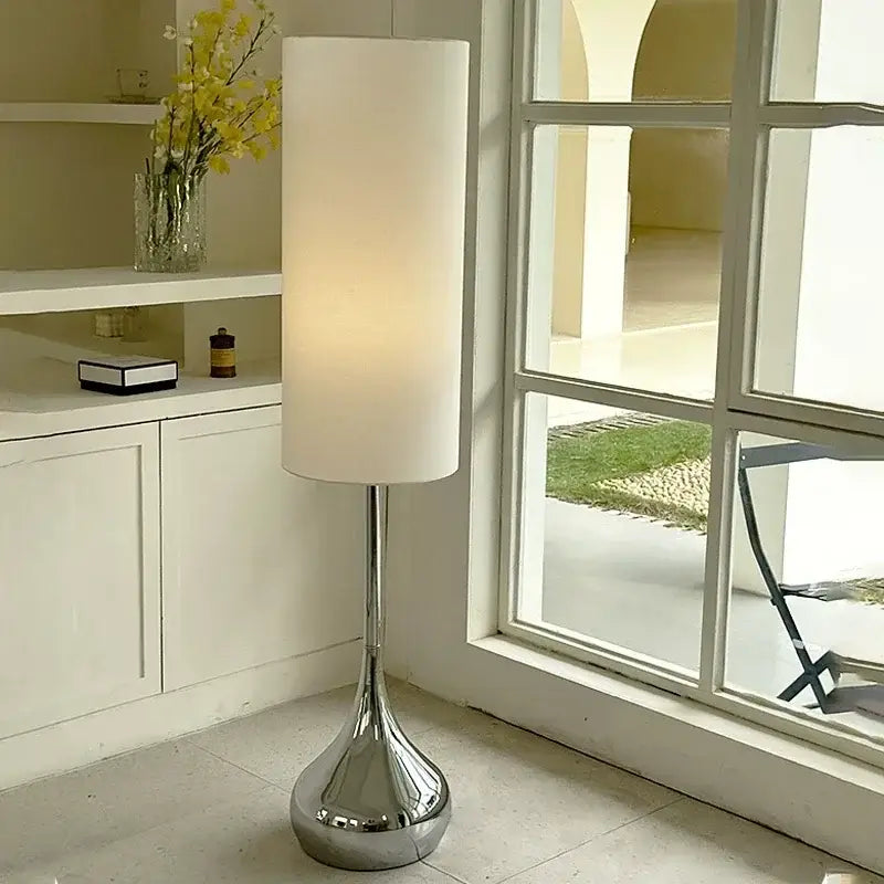 A modern floor lamp with a tall cream fabric shade and polished chrome base ideal for living room decorbites cream fabric