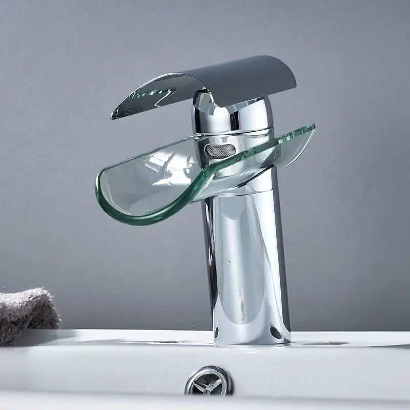 Modern chrome glass spout basin faucet with transparent glass waterfall spout and handle accents for bathroom use