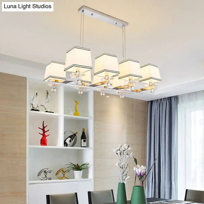 Modern chrome island pendant light with five cream fabric shades and clear crystal accents for dining rooms
