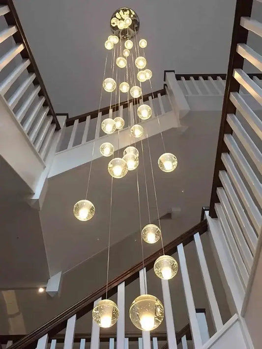 A modern chrome spiral pendant light with crystal pendant glass globes and stainless steel chassis for stairwells