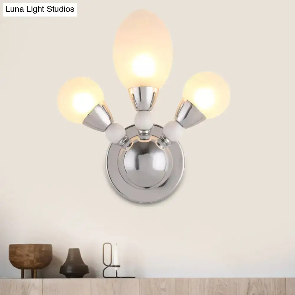 Modern chrome wall light with three frosted white glass shades designed as a bedroom wall sconce