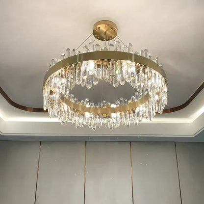 A modern circular gold decorbites crystal chandelier featuring double rings and cascading clear crystal prisms