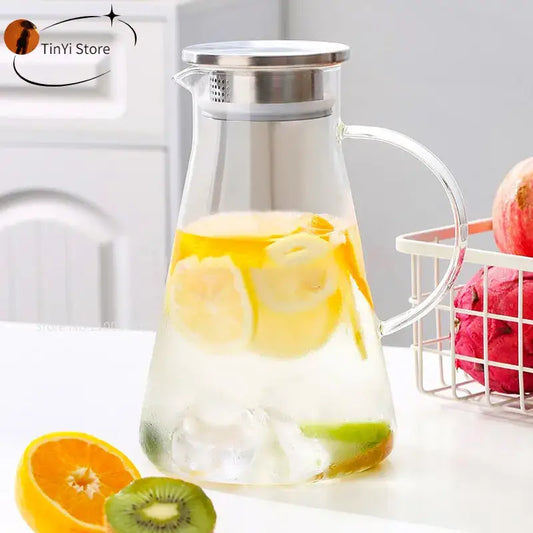 Modern clear borosilicate glass pitcher with stainless steel lid and handle filled with ice water and lemon slices