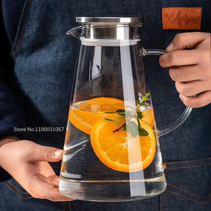 Modern clear borosilicate glass pitcher with stainless steel lid filled with water orange slices and mint leaves