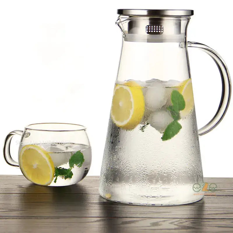 Modern clear borosilicate glass pitcher with stainless steel lid filled with ice lemon slices and mint leaves