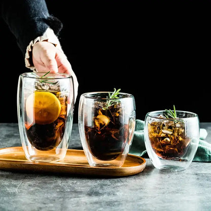 Set of three clear modern double wall glass cups with ice lemon slices and rosemary for dining room use