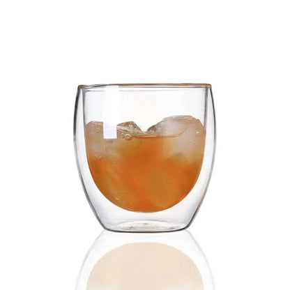 Modern clear double wall glass cup filled with amber liquid and ice cubes for dining room use