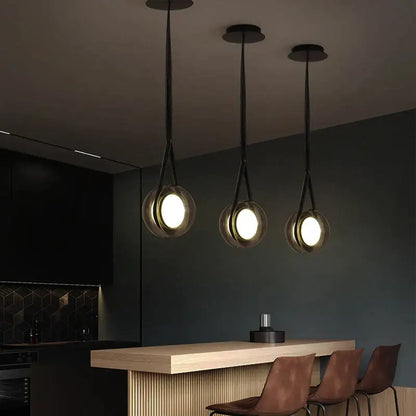 Three modern clear glass decorbites designer pendant lights with black cords hang from the ceiling for bedroom decor