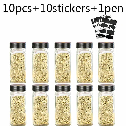 Set of ten modern clear glass seasoning jars with black lids filled with dried herbs for kitchen use