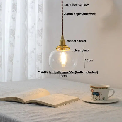 A warm-glowing modern glass led pendant lamp with clear globe, white ceramic, brass copper socket, and iron canopy