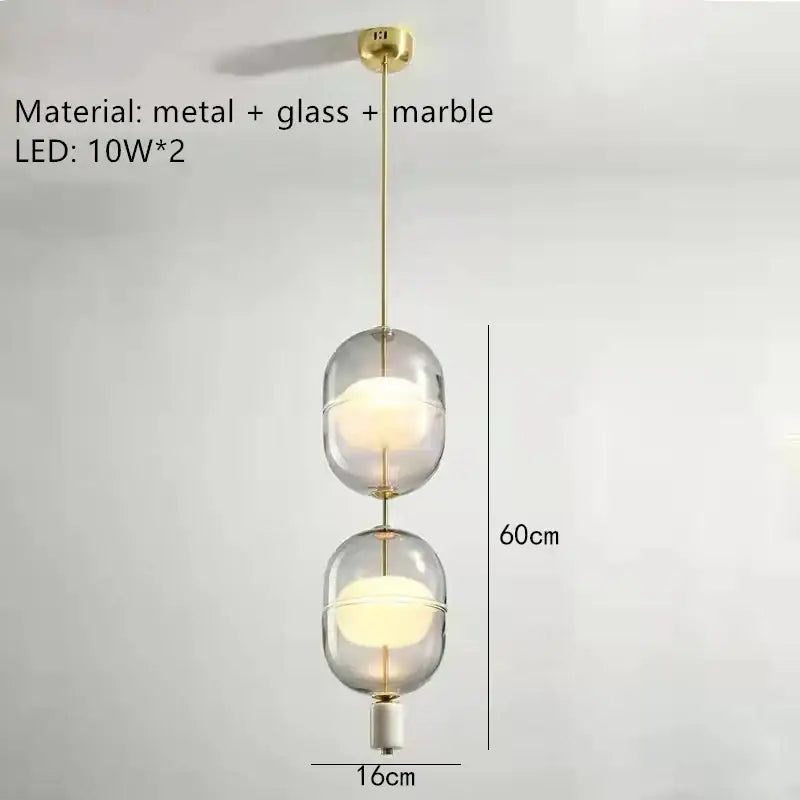 Modern pendant light with two oval clear gray amber glass globes, brass metal accents, and marble details for dining room decorbites clear gray