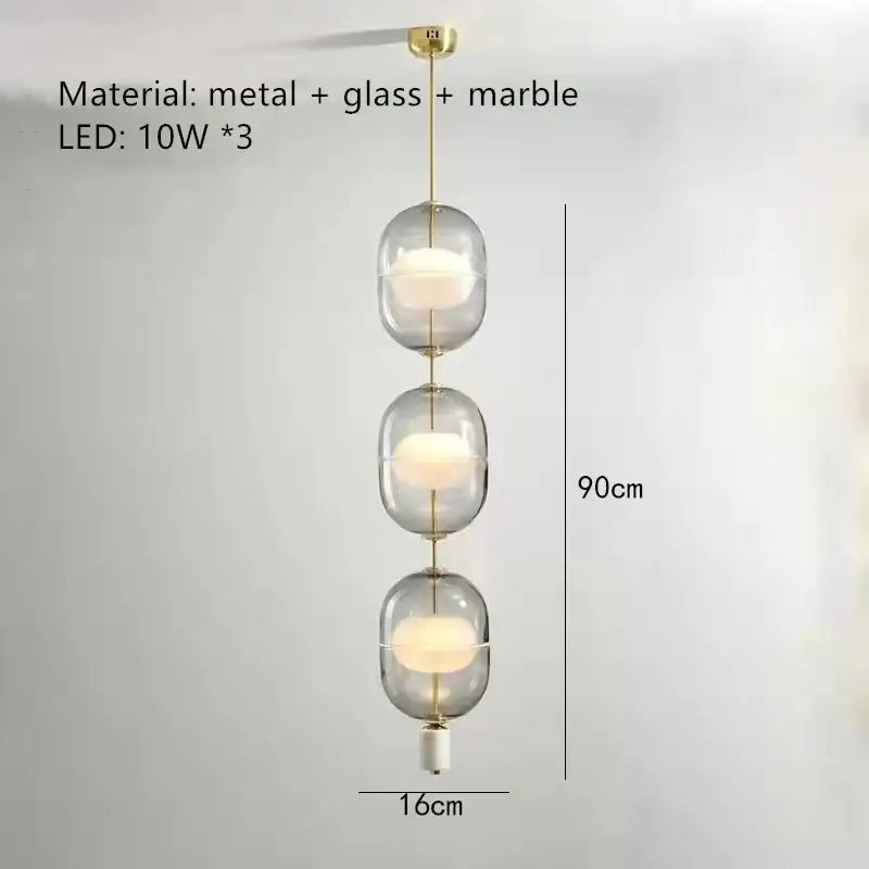 Modern clear gray amber glass pendant light with three translucent orbs, brass accents, and marble base for dining room decorbites