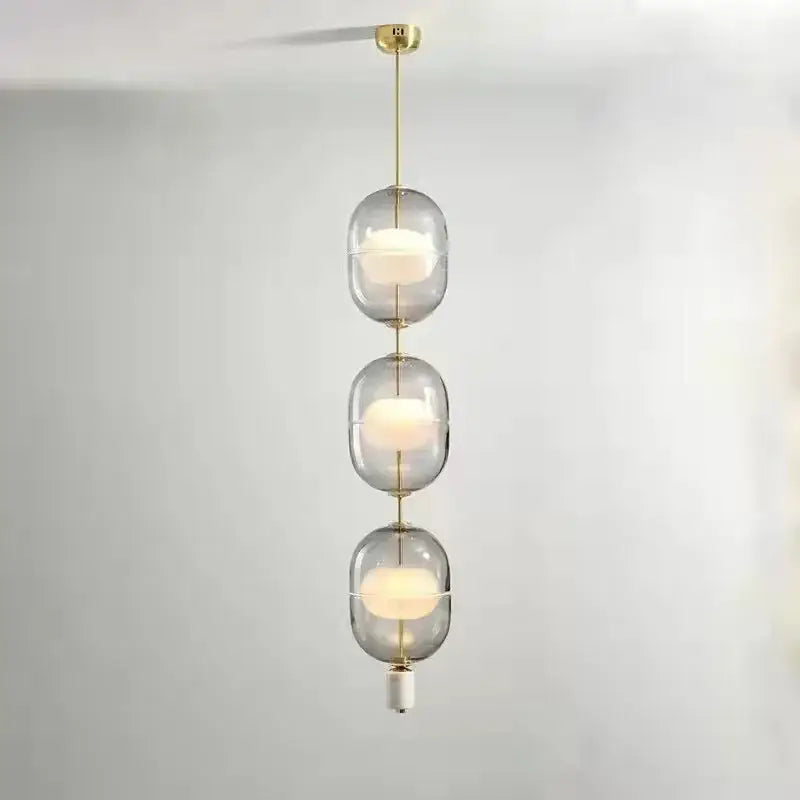 Modern three-tiered pendant light with clear gray amber glass globes and brass accents for dining room decorbites clear gray