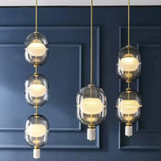Modern pendant light with stacked clear gray amber glass orbs and brass accents for dining room decorbites clear gray