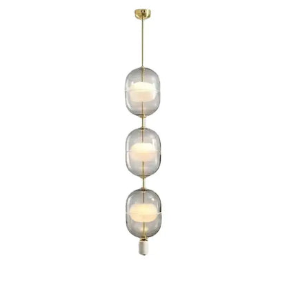Modern pendant light with three stacked translucent clear gray amber glass orbs and brass rods for dining room decorbites clear gray