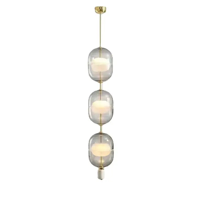 Modern pendant light with three stacked translucent clear gray amber glass orbs and brass rods for dining room decorbites clear gray