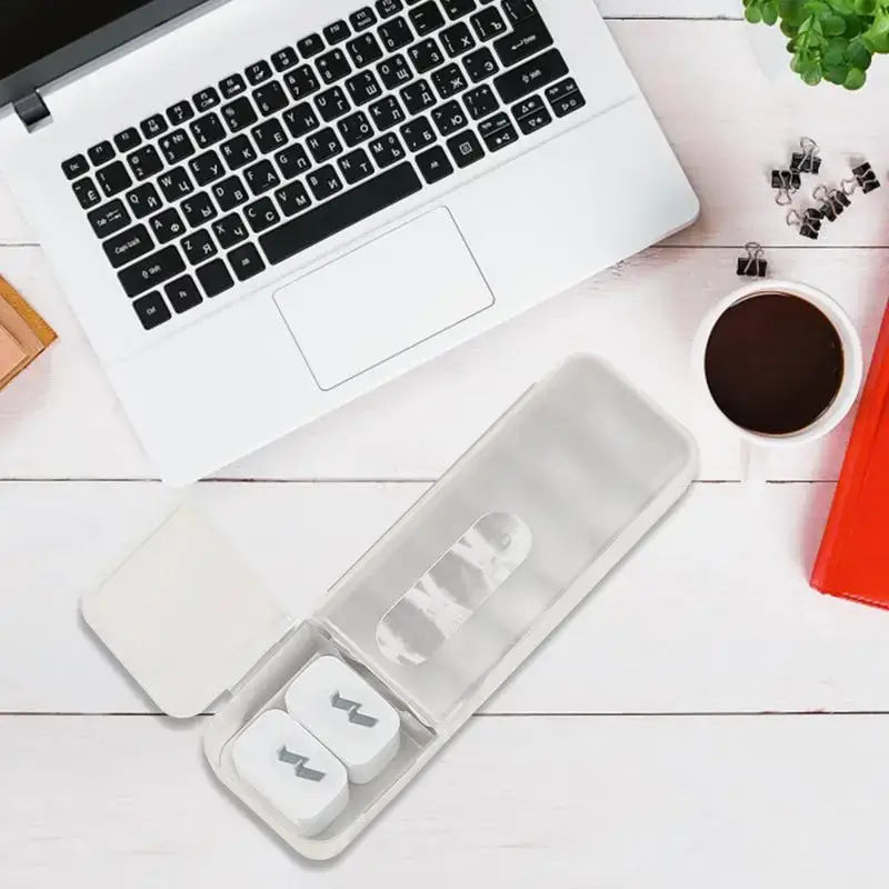Transparent plastic case holding white wireless earbuds with black logos inside modern clear and gray decorbites cable box