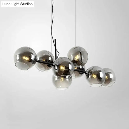 Modern black metal lighting fixture with clear smoke glass spheres and gold accents for dining room illumination