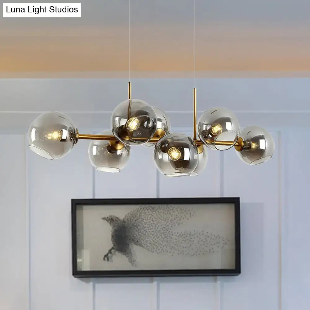 Modern black and gold lighting fixture with brass finish and clear smoke glass globe shades for dining room use