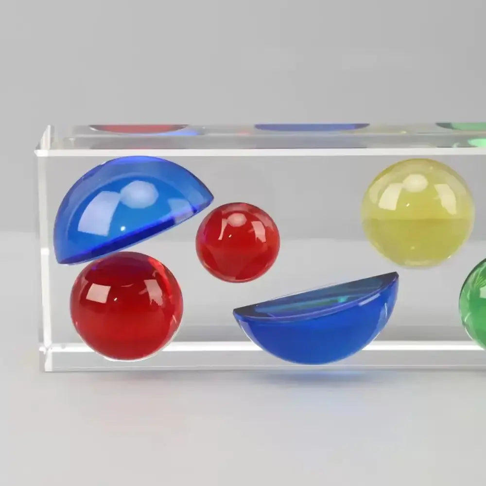 Clear acrylic container holding colorful crystal spheres and half-spheres in red blue yellow and green for living room decor