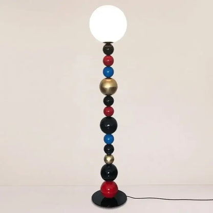 A modern floor lamp with colorful glass ball spheres in red blue black and gold and a white globe bulb for living room