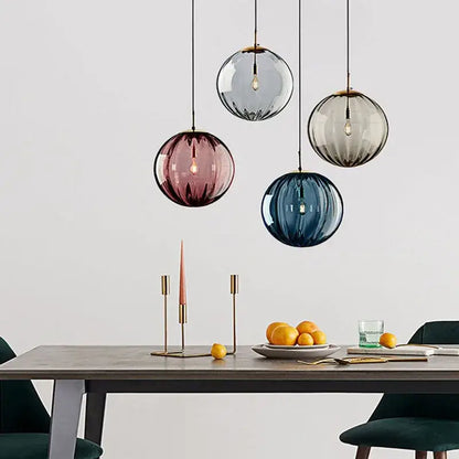 Four spherical frosted glass ball lustre pendant lights in gray rose and blue hang above a dining table