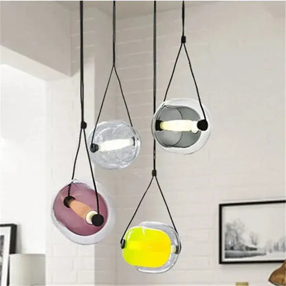 Modern colorful glass capsule led pendant light with translucent orbs suspended by black cords for kitchen bar use