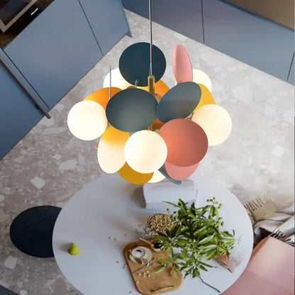 A modern colorful glass decorbites branch chandelier with matte pastel and dark circular shades above a round table